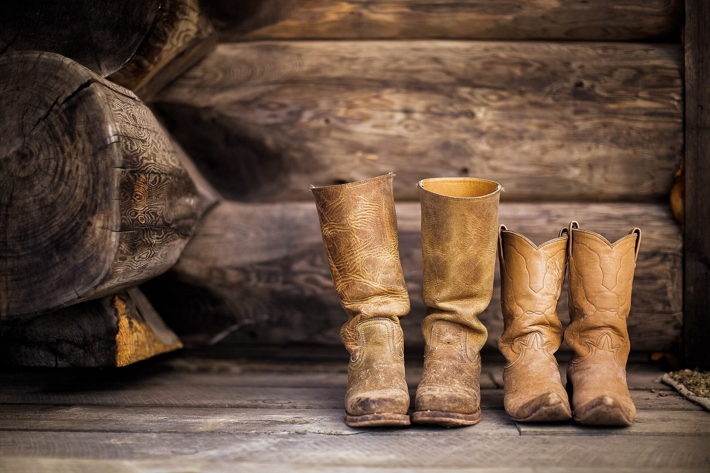 A pair of worn leather boots on a plank floor.